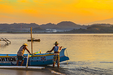 Indonesian men with a boat at sunrise time, Gerpuk, Lombok, Indonesia