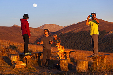 Friends hang out by the campfire outside the Jackal Hut, White River National Forest, Colorado.