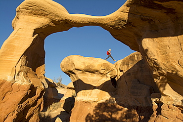 A young girl hiking along the edge of Metate Arch in the  Devil's Garden, Hole in the Rock Road, Grand Staircase-Escalante National Monument, Escalante, Utah.