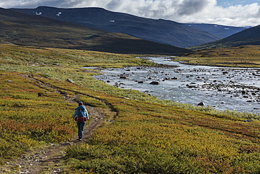 Hiker on trail through Tjäktjavagge south of Singi hut, Kungsleden trail, Lapland, Sweden