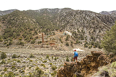 SURPRISE CANYON, DEATH VALLEY, CA, USA. A young man takes a break at an overlook of an abandoned silver mine in a dry, remote valley.