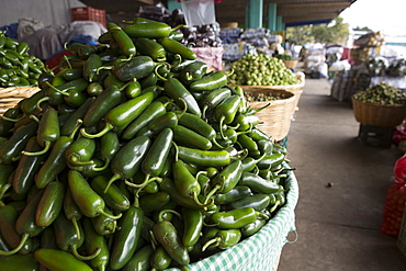 A closeup view of a basket of green chili peppers.