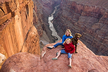 A mother and daughter and their dog sitting on the edge of Toroweap Overlook above the Colorado River, Grand Canyon National Park, Fredonia, Arizona.