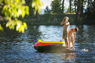 Two Boys swimming and playing on an inflatable raft in Duck Bay on Payette Lake in McCall, Idaho