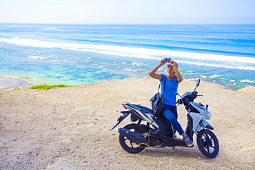 Young woman travelling by bike and taking pictures with her phone