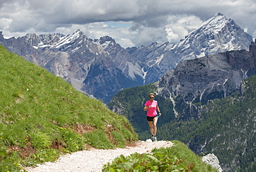 A Woman Trail Running At The Cinque Torri Area With The Croda Da Lago And Lastoi De Formin In The Background