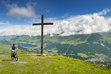 Mountain Biker Riding A Mountain Bike Near A Cross Sign On The Top Of Mountain