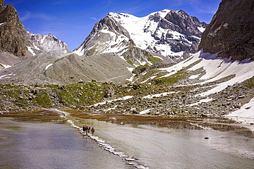 Group Of Hikers Making Their Way In The Distance Along The Stone Cross Bridge