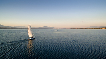 Two Sailboats Gently Gliding Across The Lake