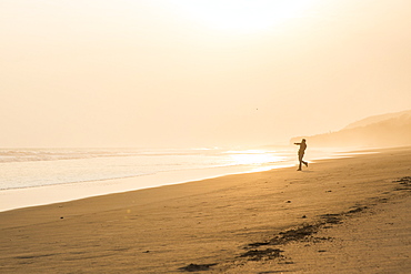 A Man Throws Beach Rocks Into The Ocean At Sunset At Popoyo Beach, Nicaragua