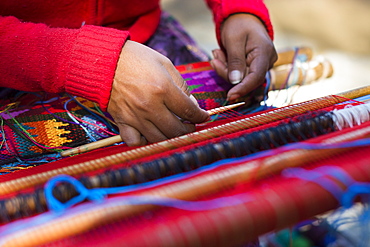 A Mayan Woman Works Carefully As She Weaves The Brightly Colored Traditional Guatemalan Huipil