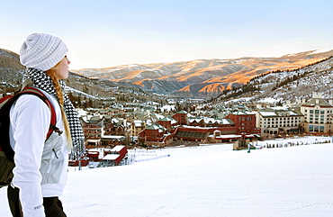 Woman With A Backpack Looks Out Over Beaver Creek Village And Mountains At Dusk