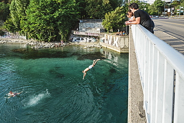 Man Jumping Off A Bridge Into The Rhone River In Geneva, Switzerland