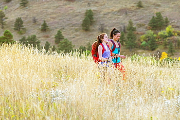 Two Female Hikers Smiling While Walking On A Trail Beneath The Flatirons In Colorado