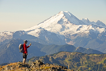 A Backpacker Checks His Phone While Hiking In North Cascades National Park