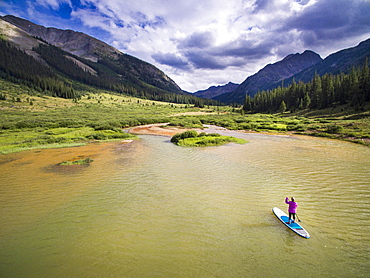 A female paddleboarding on a high alpine lake before a thunderstorm