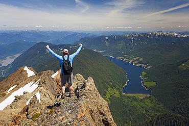 Hiker celebrating in victory pose after climbing Lady Peak in Cheam Mountain Range