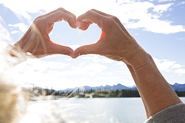 POV to woman's hands framing mountain lake