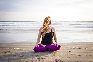 Woman Sitting On Beach Doing Yoga In Rhode Island On Windy Day