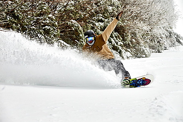 A snowboarder slashing powder inbounds at Sugarbush, VT.