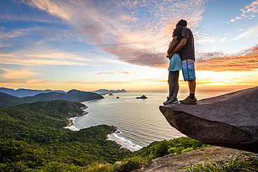 Couple on the edge of the mountain in Pedra do Telégrafo near Barra de Guaratiba, Rio de Janeiro, Brazil