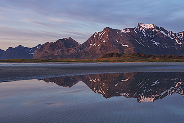 Midnight sun mountain reflection on Ytresand beach, Moskenesøy, Lofoten Islands, Norway
