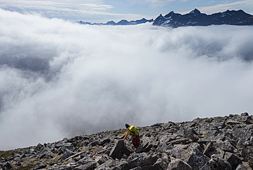 Female hiker hiking in cloudy weather while descending from summit of Volandstind mountain peak, Lofoten Islands, Norway