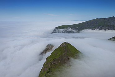 Mountain peaks emerge above fog at Unstad, Vestågøy, Lofoten Islands, Norway