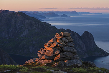 Summit cairn on Veinestind lit by setting sun, Moskenesøy, Lofoten Islands, Norway