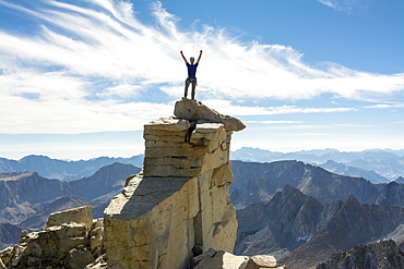 A man standing on the Mount Darwin summit along the 8.5 mile Evolution Traverse, John Muir Wilderness, Kings Canyon National Park, Bishop, California.