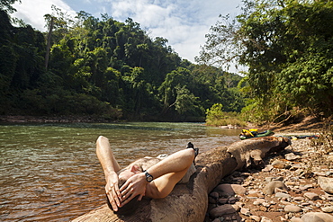 Robert Hahn rests on a sunny log on the shore of the Nam Ou RIver, Laos.