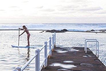 SUP girl in a natural swimming pool