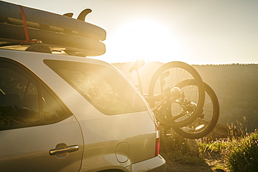 Vehicle loaded with mountain bikes and Stand Up Paddle Boards at sunset