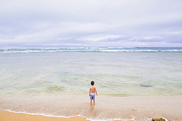 Haleiwa Beach on Oahu in Hawaii with a young five year old bot playing in the Ocean water.