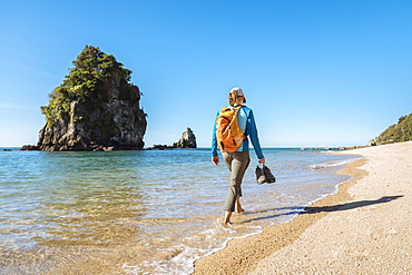 A woman is walking on a beach in Abel Tasman National Park