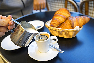 Cream poured into an espresso at a brasserie in Saint Michel, Paris, France