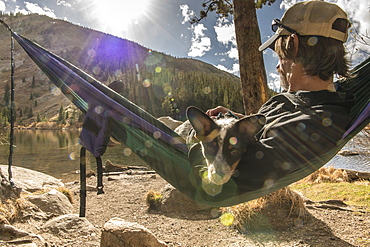 Man & dog in hammock by mountian lake