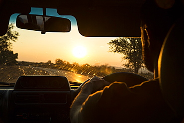 A male drives his truck towards the sunset in Zimbabwe