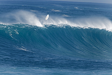 A surfer wiping out on a huge wave at Waimea Bay.