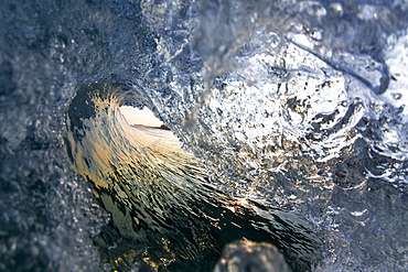 A wave breaking towards the shoreline on the north shore of Oahu, during sunrise.