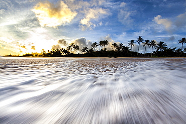 A time lapse of a wave rushing back down the beach on the north shore of oahu, during sunrise.