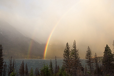 A double rainbow forms over St. Mary Lake in Glacier National Park during a sunrise rainstorm.