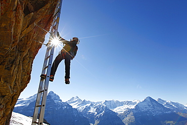 A climber on a ladder of the Klettersteig to the top of the Schwarzhorn, a mountain above Grindelwald in the Swiss Alps.