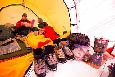 Two mountaineers are laying inside a tent at High Camp on Denali in Alaska. Early morning they are going for a summit push to the highest mountain of Northern America.