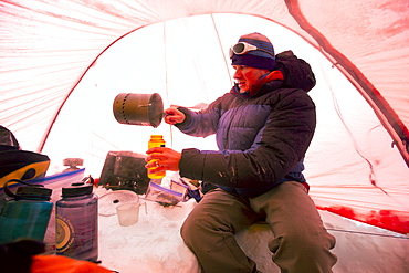 A mountaineers is melting snow to get drinking water, inside a tent at High Camp on Denali in Alaska. Early morning they are going for a summit push to the highest mountain of Northern America.