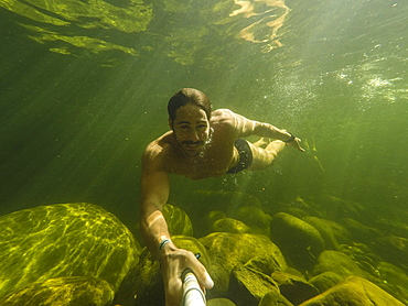 Shirtless man taking underwater selfie in Poco Verde (Green Pool), Guapimirim Sector of Serra dos Orgaos National Park, Rio de Janeiro, Brazil