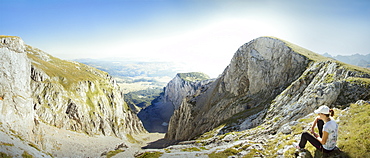 Hiking girl resting on top of the big erosion rift on Bioc mountain, Bosnia and Herzegovina. Sunny day with no clouds.