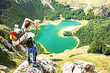 Hiker standing on the rock, high above heart shaped lake in Montenegro. Trnovacko lake on Bioc mountain.