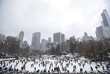 Crowd of people ice skating on Wollman Rink in Central Park in New York City during the winter, USA