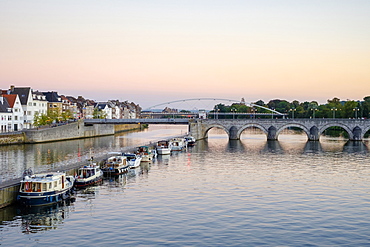 Photograph of Meuse River with bridge, boats and buildings on bank, Maastricht, Limburg, Netherlands